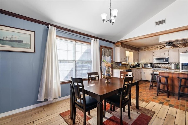 dining area featuring lofted ceiling, crown molding, sink, light wood-type flooring, and ceiling fan with notable chandelier