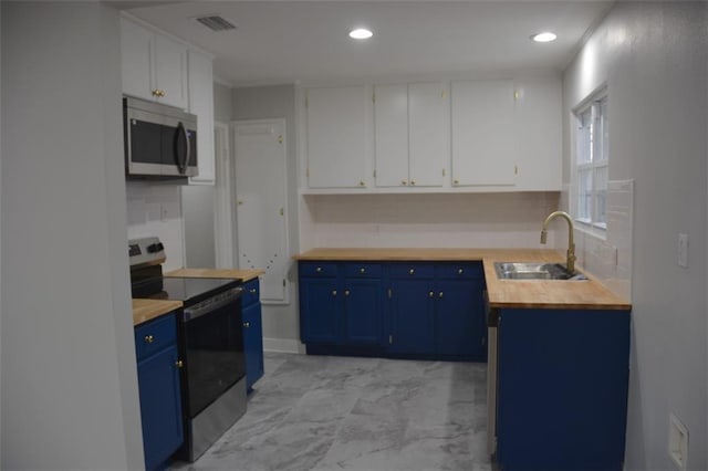kitchen with blue cabinetry, wooden counters, appliances with stainless steel finishes, and a sink