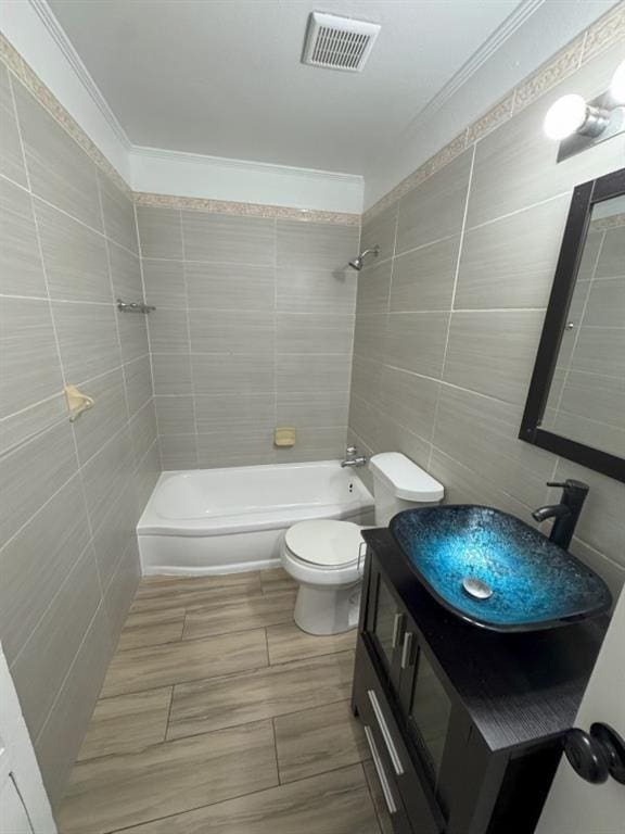 bathroom featuring visible vents, toilet, tile walls, and bathing tub / shower combination