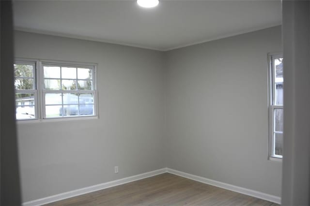 unfurnished room featuring a healthy amount of sunlight, baseboards, and wood finished floors