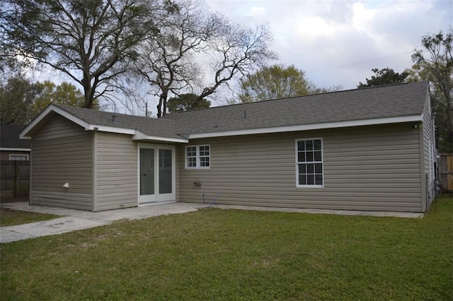 back of property with a lawn and fence