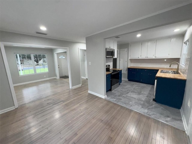kitchen featuring visible vents, a sink, blue cabinetry, open floor plan, and appliances with stainless steel finishes