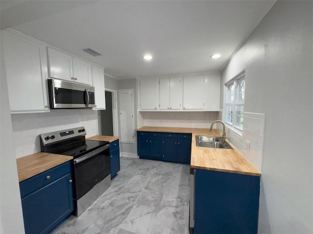 kitchen featuring blue cabinets, wood counters, appliances with stainless steel finishes, and visible vents