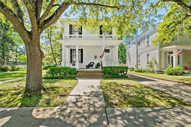 view of front of house featuring a balcony, a front lawn, and covered porch