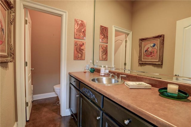 bathroom with toilet, vanity, and baseboards