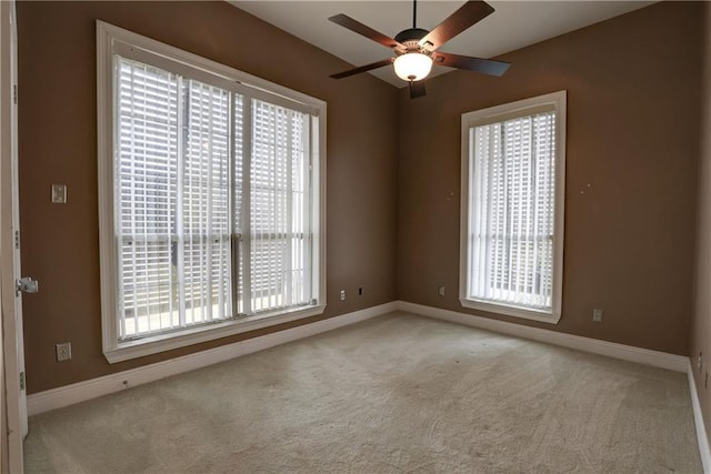 carpeted spare room featuring plenty of natural light and ceiling fan