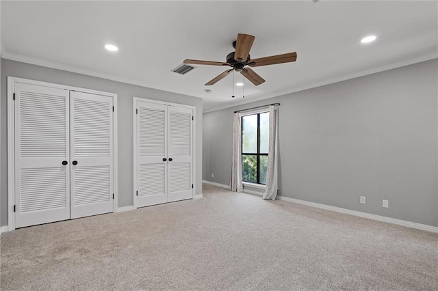 unfurnished bedroom featuring light carpet, two closets, ornamental molding, and ceiling fan