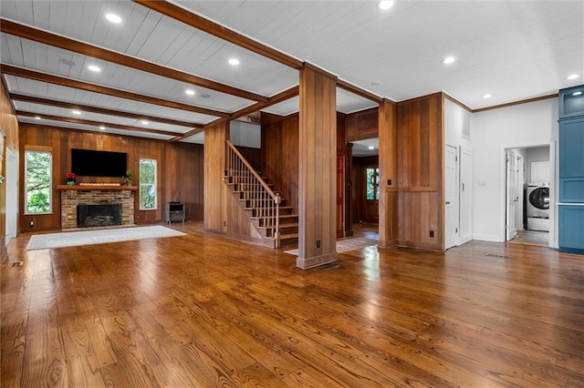 unfurnished living room featuring wood walls, a fireplace, beam ceiling, and hardwood / wood-style flooring