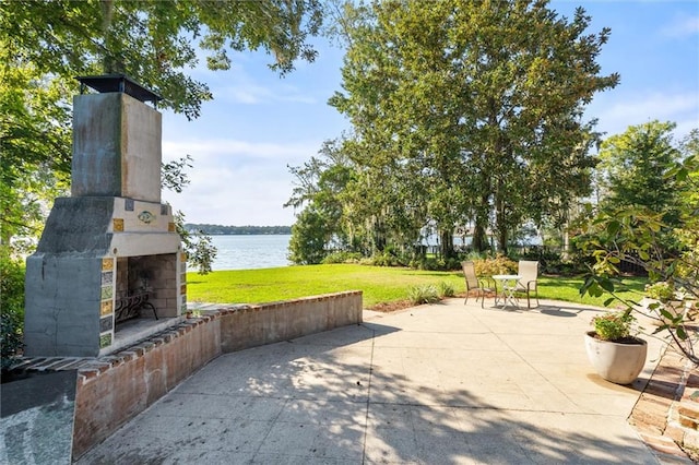 view of patio featuring a water view and an outdoor fireplace