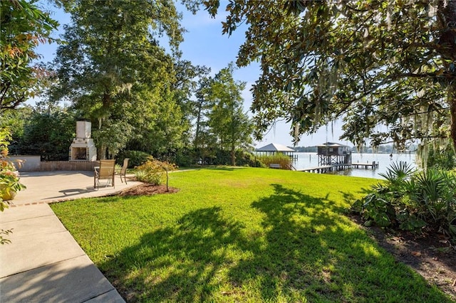 view of yard with a boat dock, a water view, and a patio area