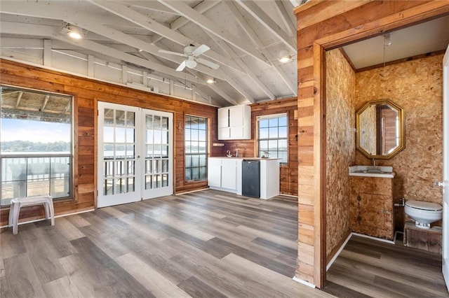 interior space featuring wood-type flooring, vaulted ceiling with beams, and white cabinetry