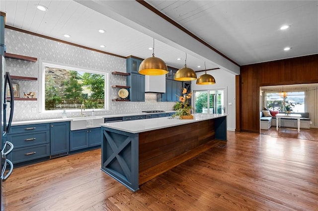 kitchen with hardwood / wood-style flooring, a healthy amount of sunlight, hanging light fixtures, and blue cabinets