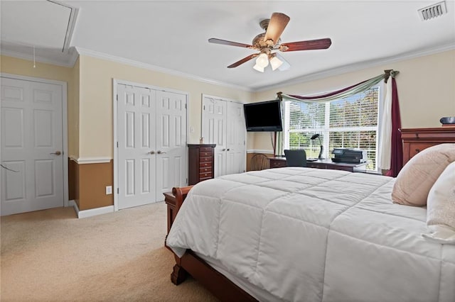 bedroom with carpet, ceiling fan, ornamental molding, and multiple closets