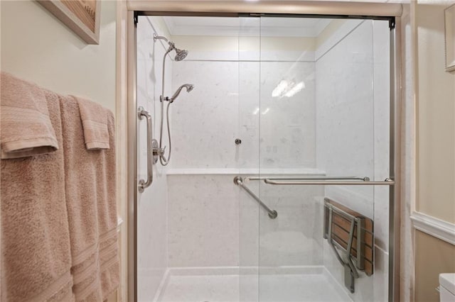 bathroom featuring a shower with shower door, toilet, and ornamental molding