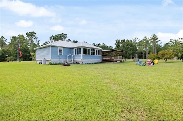 rear view of house with a lawn and a sunroom