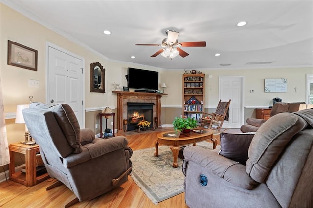 living room with crown molding, light hardwood / wood-style flooring, and ceiling fan