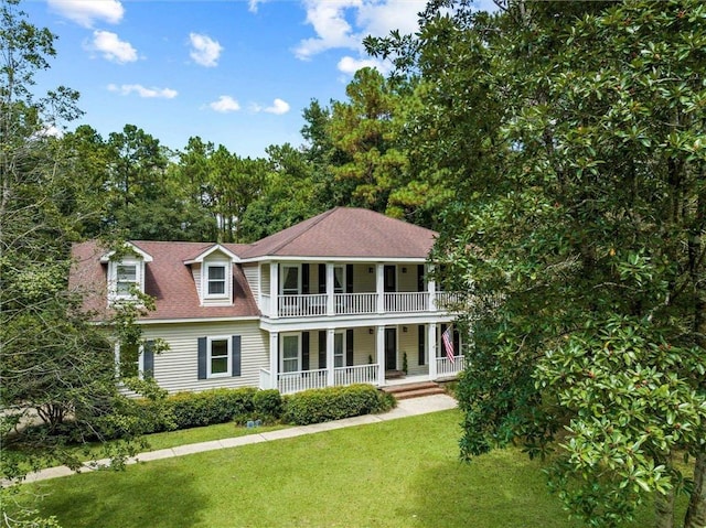 view of front of house featuring a balcony and a front lawn