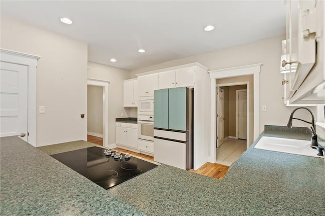 kitchen with light wood-type flooring, white appliances, white cabinetry, and sink