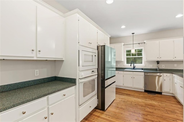 kitchen with light wood-type flooring, decorative light fixtures, stainless steel appliances, white cabinetry, and sink