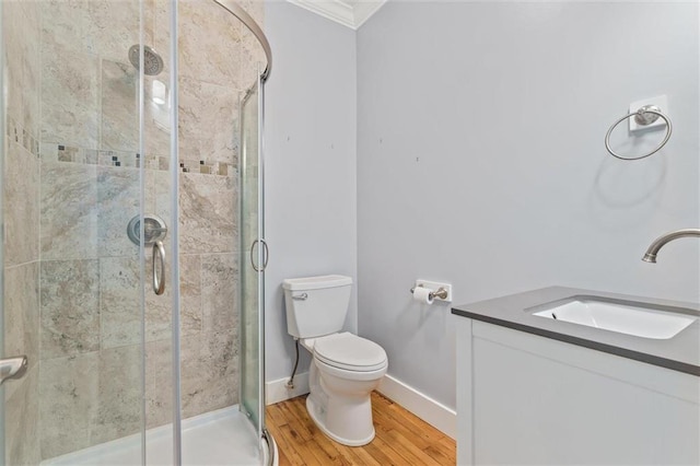 bathroom with hardwood / wood-style floors, walk in shower, toilet, vanity, and ornamental molding