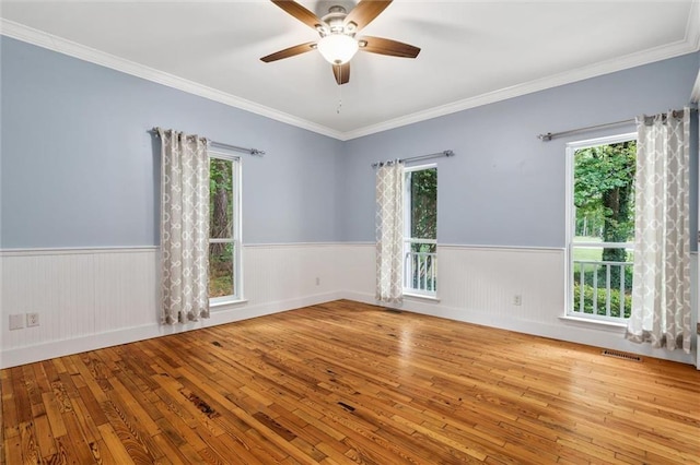 spare room with light wood-type flooring, ceiling fan, a wealth of natural light, and ornamental molding