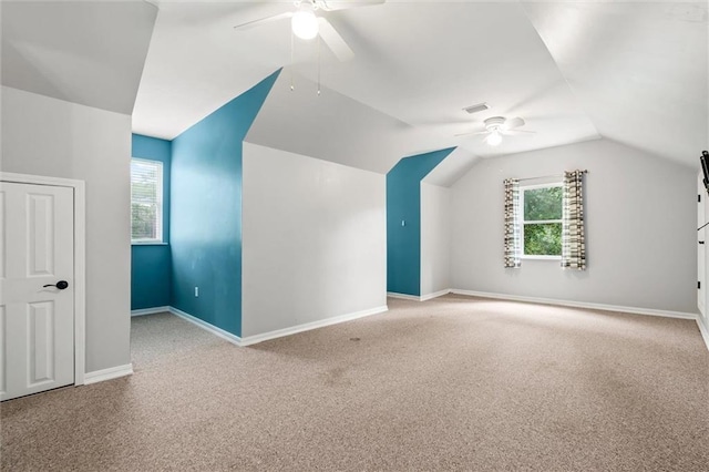 additional living space with lofted ceiling, a healthy amount of sunlight, ceiling fan, and light carpet