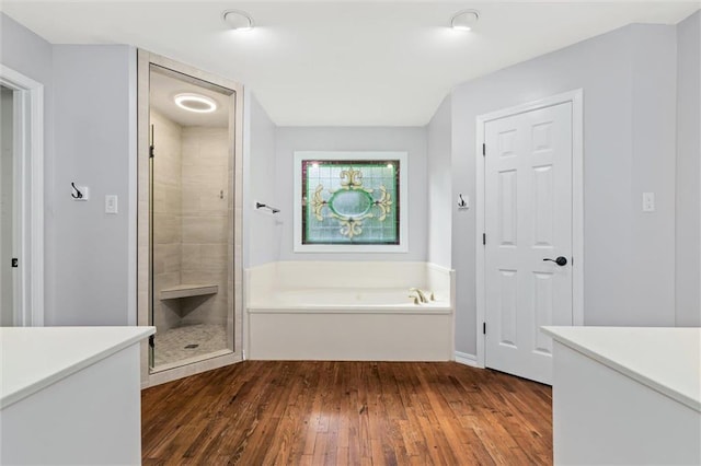 bathroom with vanity, hardwood / wood-style flooring, and plus walk in shower