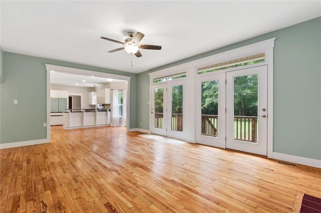 unfurnished living room featuring ceiling fan and light hardwood / wood-style flooring