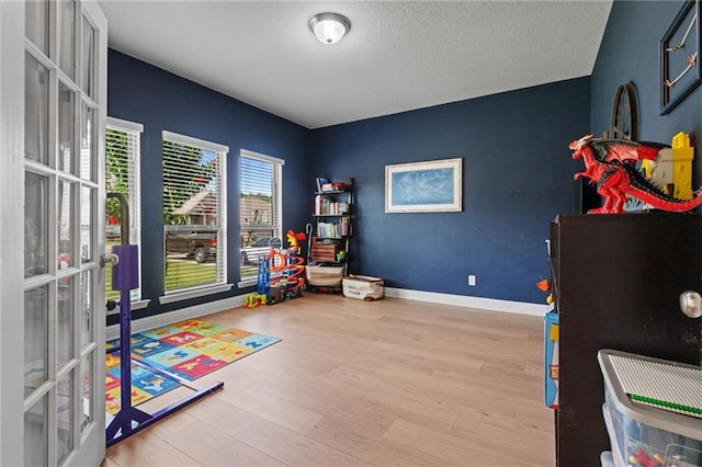 13077 Tara Point Dr, Mobile, AL 36695 - playroom featuring french doors, wood finished floors, baseboards, and a textured ceiling