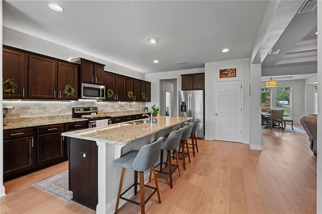 13077 Tara Point Dr, Mobile, AL 36695 - kitchen with stainless steel appliances, a kitchen bar, backsplash, dark brown cabinets, and light stone countertops