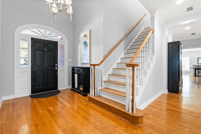 foyer featuring a chandelier, wood-type flooring, plenty of natural light, and a high ceiling