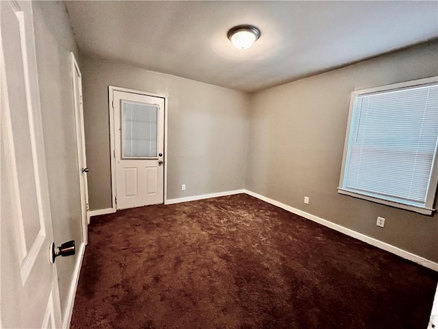 spare room with dark colored carpet