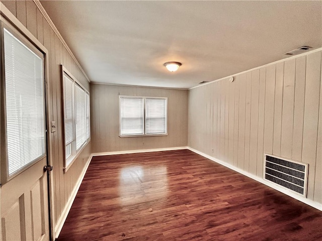 empty room with hardwood / wood-style flooring and crown molding