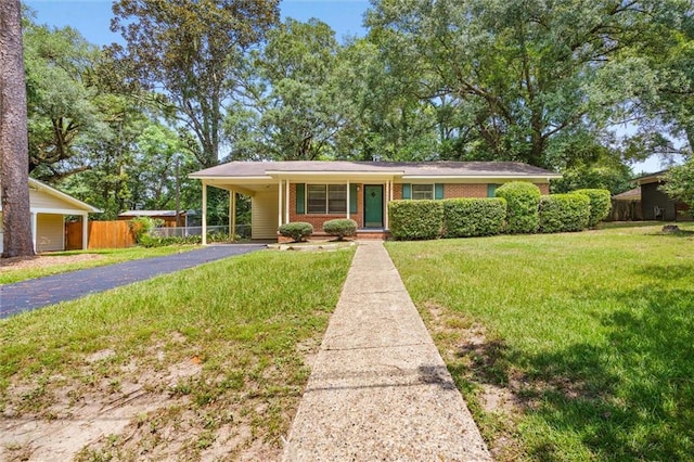 view of front of property featuring driveway, an attached carport, fence, a front yard, and brick siding