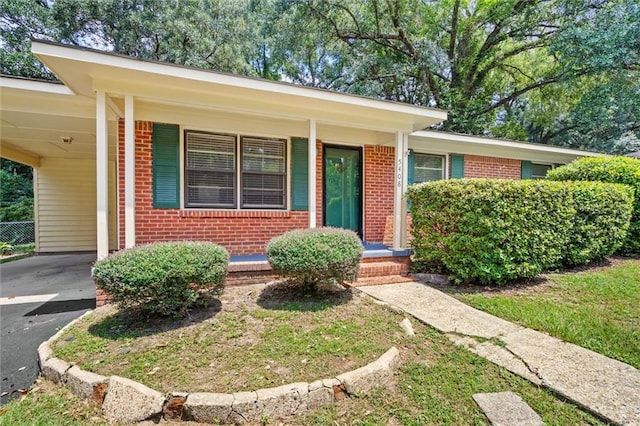 ranch-style house with driveway, brick siding, and a carport