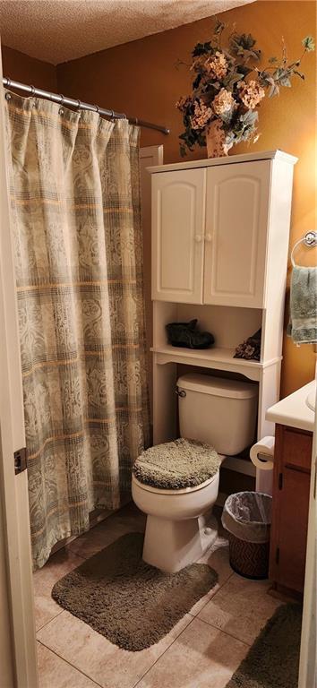 bathroom with tile patterned floors, vanity, a textured ceiling, and toilet