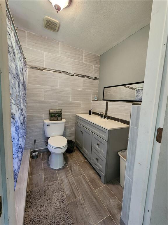 8560 Sadie Ct, Grand Bay, AL 36541 - bathroom with vanity, wood tiled floors, tile walls, and a textured ceiling
