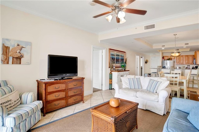 living room with crown molding, a raised ceiling, light tile patterned flooring, and ceiling fan