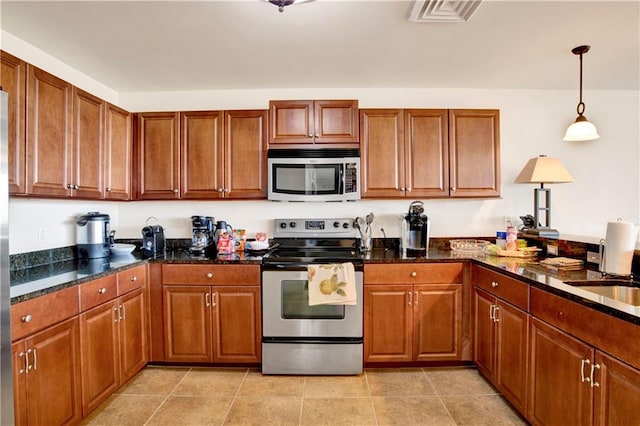 kitchen with appliances with stainless steel finishes, light tile patterned floors, decorative light fixtures, and dark stone counters