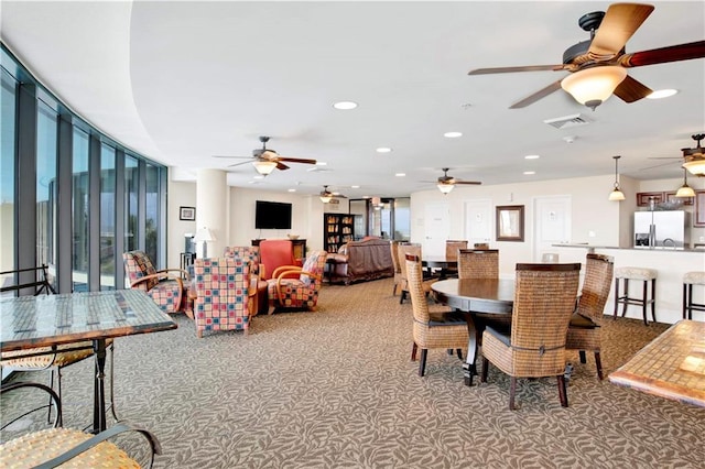 carpeted dining area with a wealth of natural light and ceiling fan