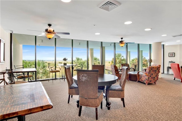 carpeted dining room with ceiling fan and a wall of windows