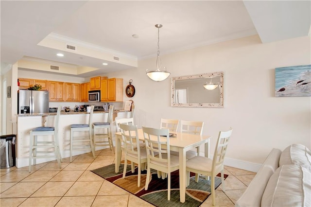 dining area featuring a tray ceiling, ornamental molding, and light tile patterned flooring