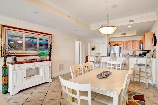 tiled dining area featuring crown molding and a tray ceiling