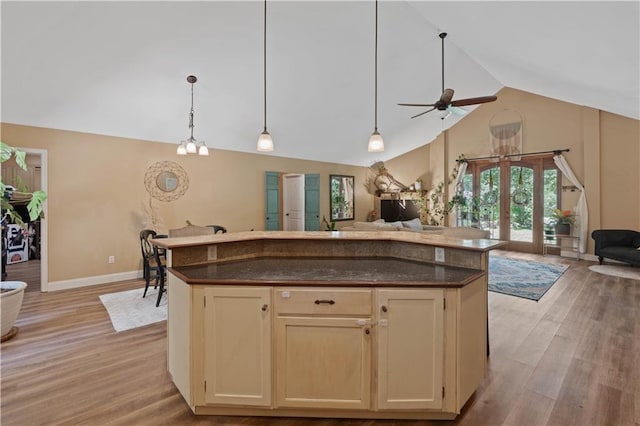 kitchen with light wood-type flooring, a kitchen island, ceiling fan, decorative light fixtures, and high vaulted ceiling