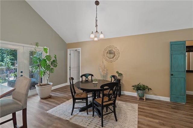 dining room with wood-type flooring, a notable chandelier, french doors, and high vaulted ceiling