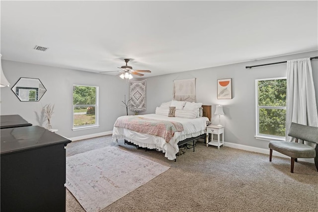 carpeted bedroom featuring multiple windows and ceiling fan