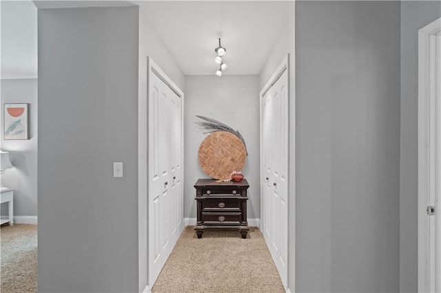 corridor featuring track lighting and light colored carpet