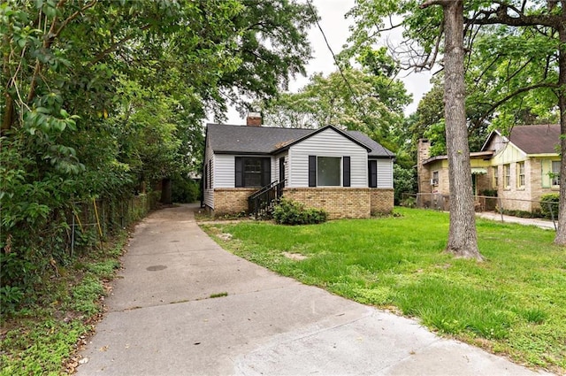 bungalow-style house featuring a front yard, concrete driveway, a chimney, fence, and brick siding