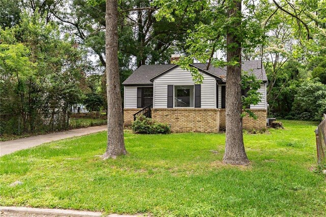 view of front of house featuring a front lawn, brick siding, and roof with shingles