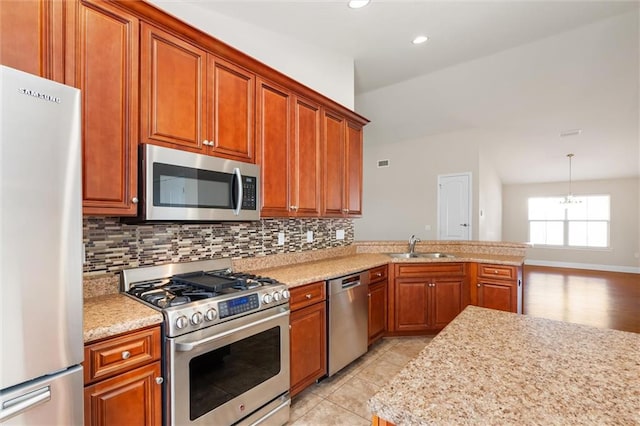 kitchen with backsplash, sink, vaulted ceiling, decorative light fixtures, and stainless steel appliances